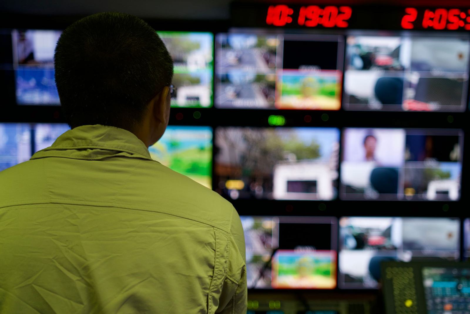 An operator watching a wall of monitors in a control room